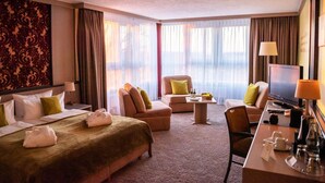 Een hotelkamer met een groot bed, een bank, een bureau en een televisie.