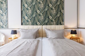 A double bed with two pillows, a headboard, bedside lamps, and a wall with a leaf pattern. - Weinberghotel Edelacker (Freyburg)