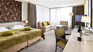 Une chambre d’hôtel comprenant un lit, un canapé, un bureau avec une télévision et une chaise.