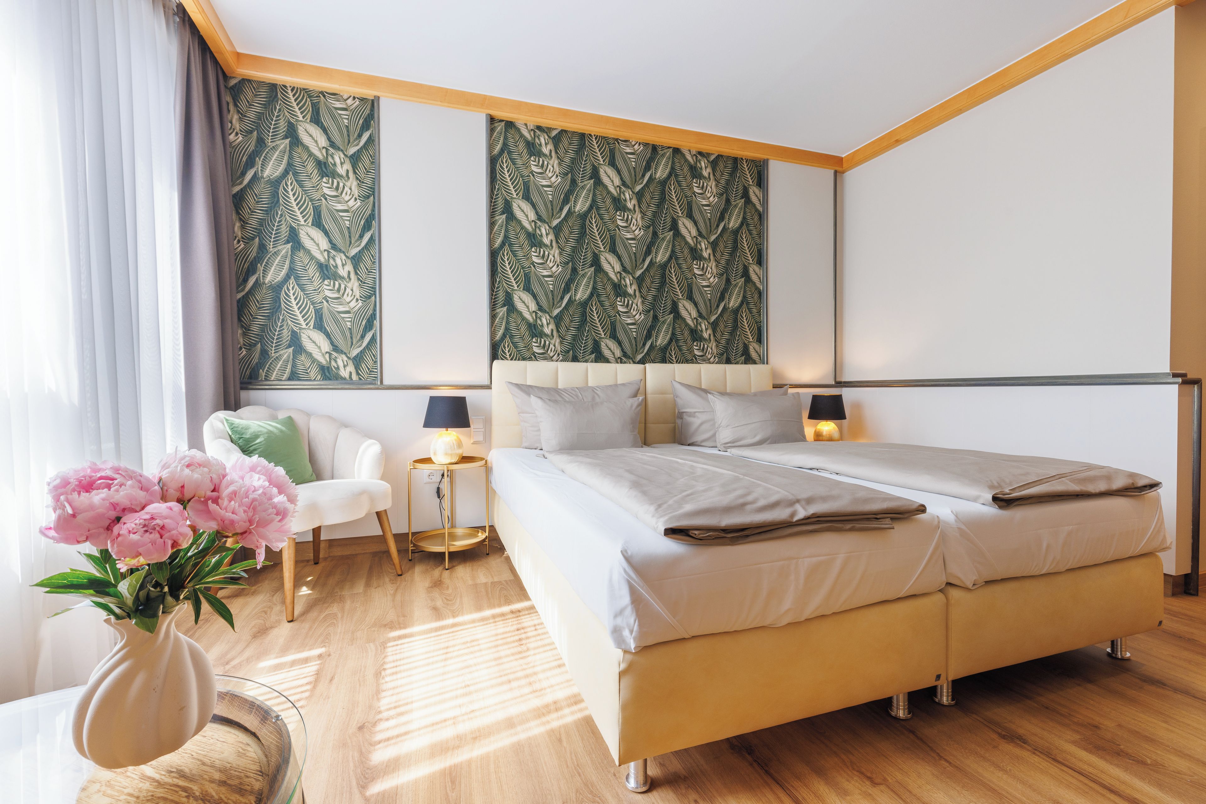 Un dormitorio moderno con una cama grande, lámparas de noche, una mesita y una silla.