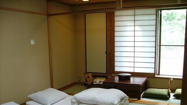 A traditional Japanese room with tatami flooring, a shoji screen, and a futon bed arrangement. - Miyajima Hotel New Kotobuki (Hatsukaichi)