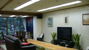 A conference room with a long table, chairs, a sofa, a television, and potted plants. - Miyajima Hotel New Kotobuki (Hatsukaichi)