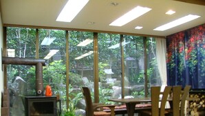 A room with a large window, a fireplace, a dining table, and chairs. - Miyajima Hotel New Kotobuki (Hatsukaichi)