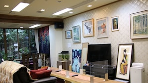 A modern living room with a sofa, a wooden table, and a TV. There are framed pictures on the wall and a fish tank. - Miyajima Hotel New Kotobuki (Hatsukaichi)