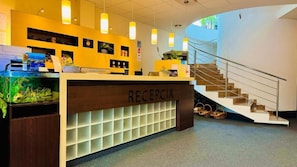 A reception area with a wooden counter, a fish tank, and a staircase leading to an upper level.