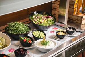A buffet table with various dishes including salads, vegetables, and a bowl of soup.