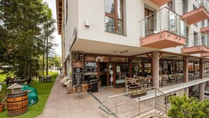 A restaurant with outdoor seating, a signboard, and a staircase leading to an upper level. - Hotel Crocus (Štrba)
