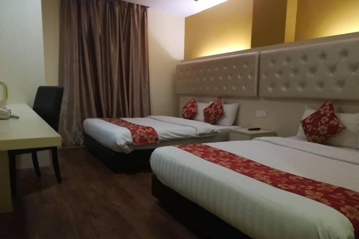 A hotel room with two beds, a desk, and a chair.