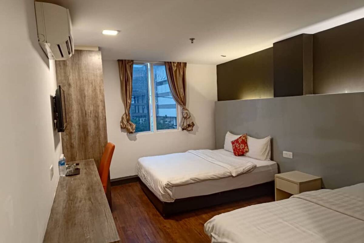 A hotel room with a bed, a desk, a chair, and a window with curtains.