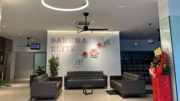 A modern reception area with a sofa, two armchairs, a coffee table, and a decorative wall with the text "SAKURA ELITE". - Sakura Elite Hotel (Kuala Lumpur)