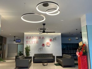 A modern reception area with a sofa, two armchairs, a coffee table, and a decorative wall with the text "SAKURA ELITE".