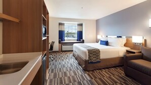 A hotel room with a bed, a sofa, a desk, and a window with curtains. - Microtel Inn & Suites By Wyndham Georgetown Delaware Beaches (Georgetown)