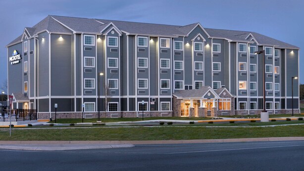 A multi-story hotel with a central entrance, large windows, and a sign indicating it is a Wyndham hotel. - Microtel Inn & Suites By Wyndham Georgetown Delaware Beaches (Georgetown)