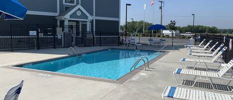 A swimming pool with lounge chairs and a building in the background.