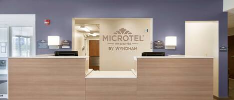 A reception desk with a sign reading "MICROTEL INN & SUITES BY WYNDHAM" and a "MANAGER ON DUTY" sign.