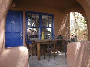 A patio with a blue door, a table, and chairs. - Casas de Guadalupe (Santa Fe)