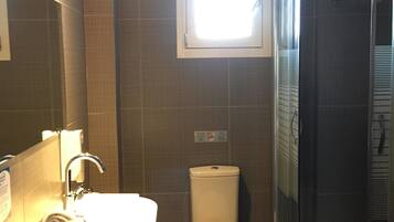 A bathroom with a sink, toilet, and a glass-enclosed shower.
