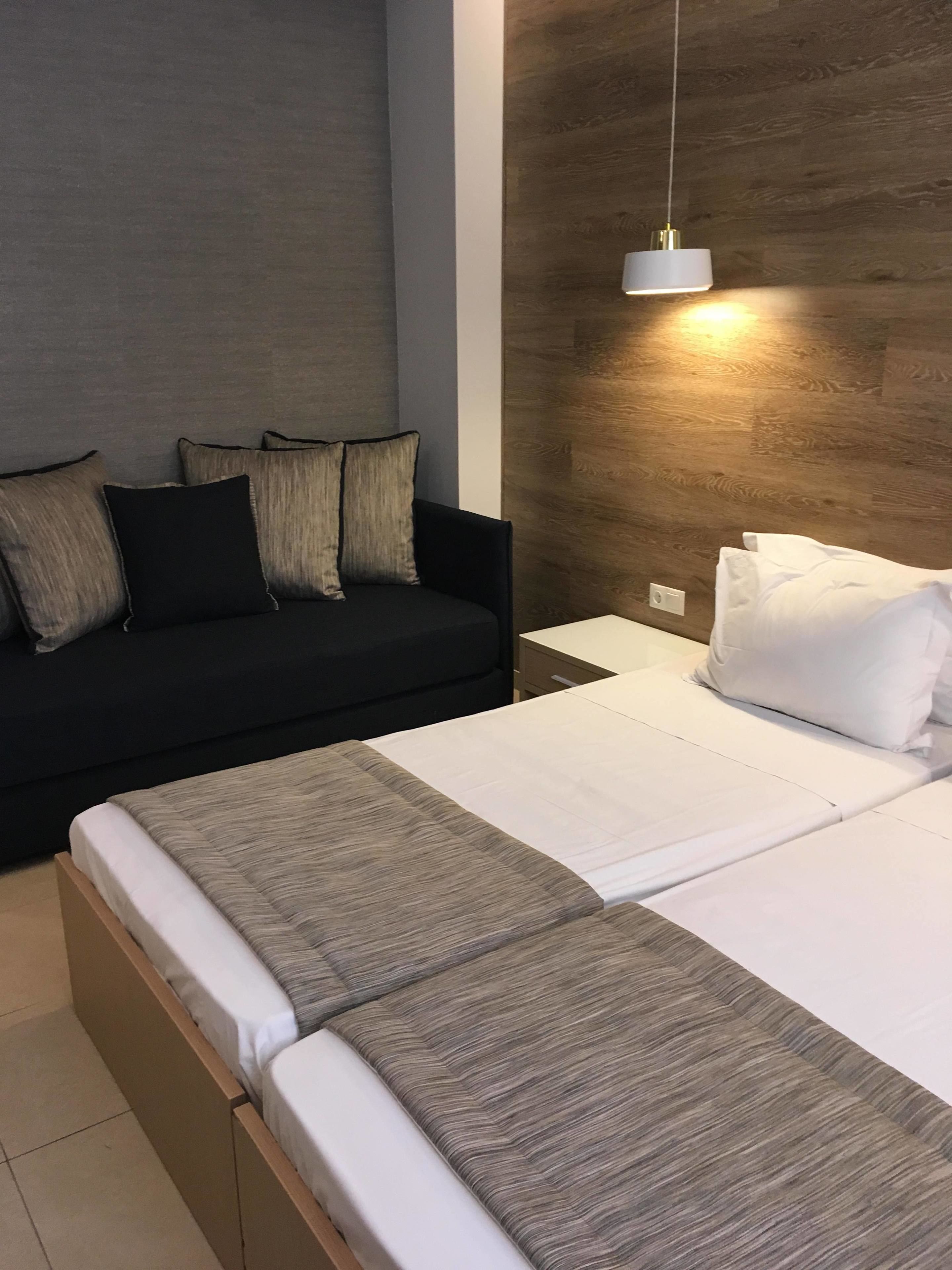Un dormitorio moderno con cama, sofá y lámpara colgante.