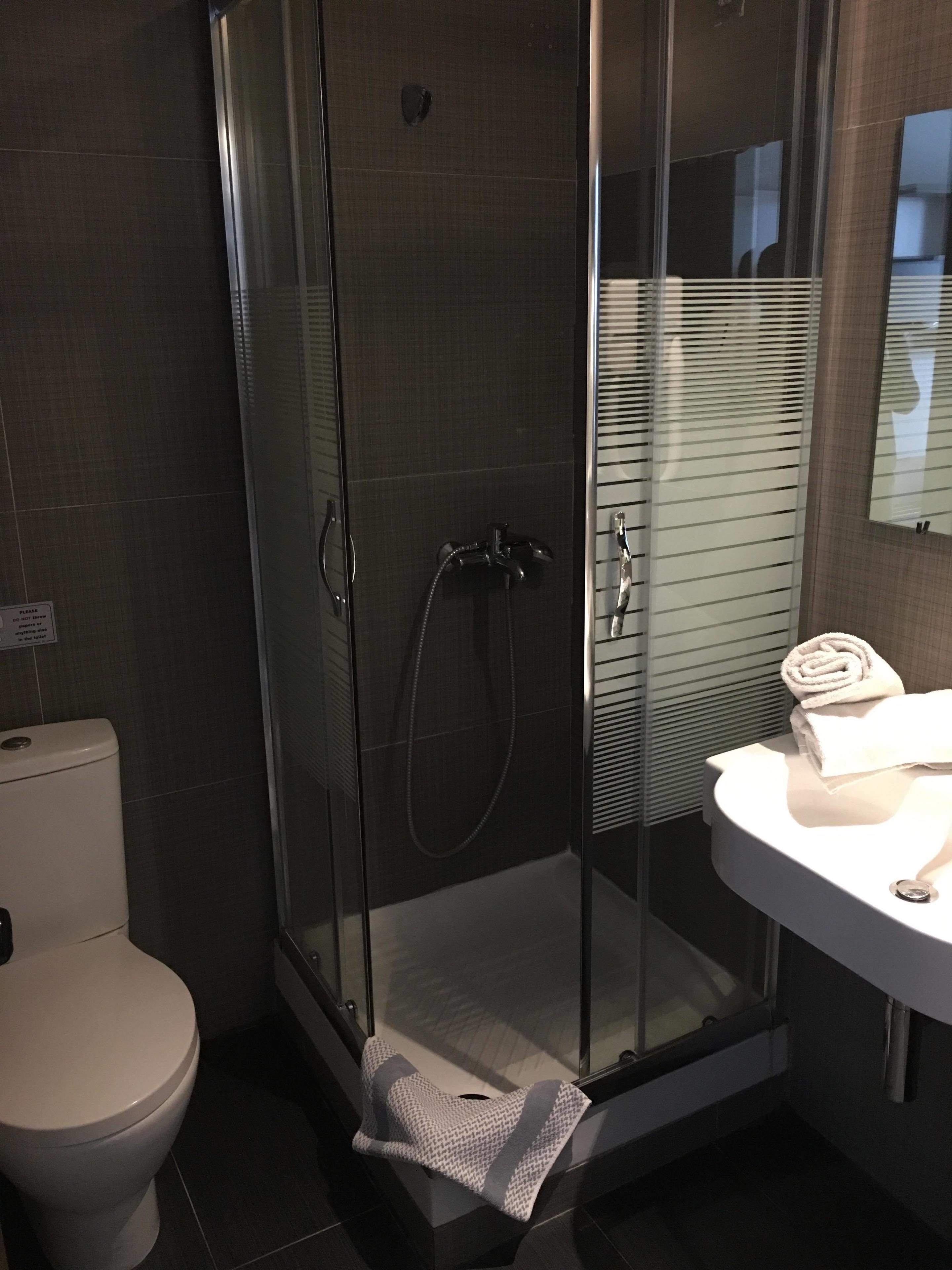 A modern bathroom with a glass-enclosed shower, a white toilet, and a sink with a towel.