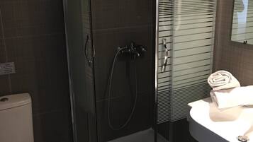 A modern bathroom with a glass-enclosed shower, a white toilet, and a sink with a towel.