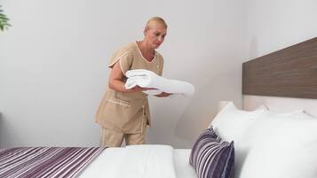 A hotel room with a neatly made bed, a headboard, and a bedside table with a lamp.