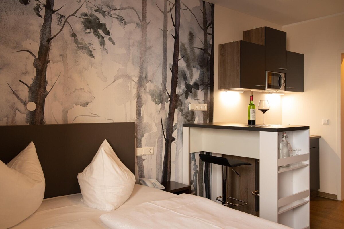 Habitación de hotel con cama, televisor de pared, minibar y chimenea.