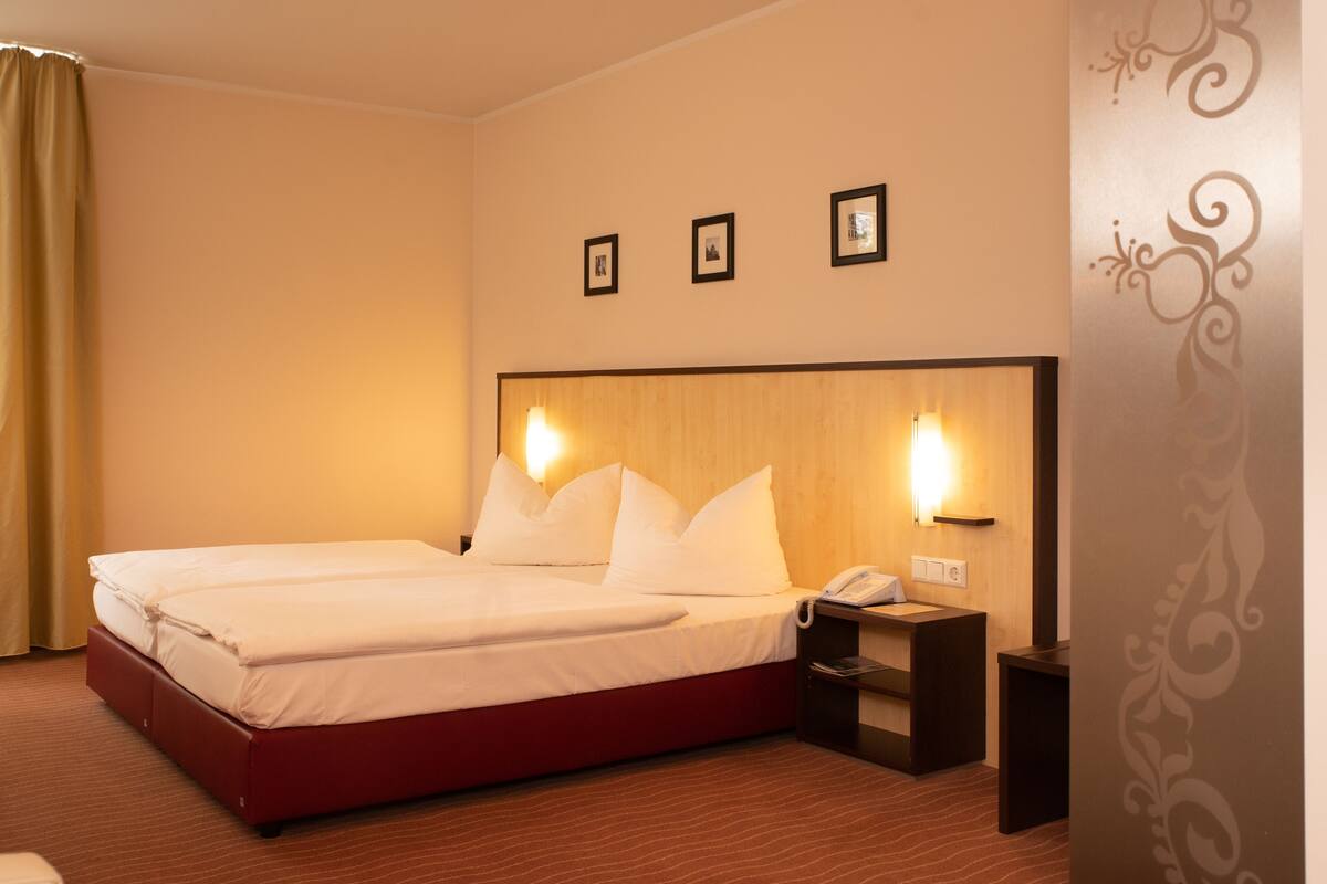 Ein Hotelzimmer mit einem großen Bett, Nachttischen und einem Telefon.