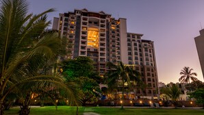 A multi-story hotel with a central atrium, surrounded by palm trees and a well-maintained lawn. - Crocs Resort & Casino (Jacó)