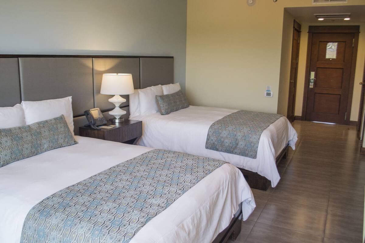 Ein Hotelzimmer mit zwei Betten, einem Nachttisch mit Lampe und einem Telefon.