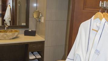 Une salle de bain avec un meuble-lavabo en bois, un miroir rond, un lavabo blanc et des toilettes blanches.