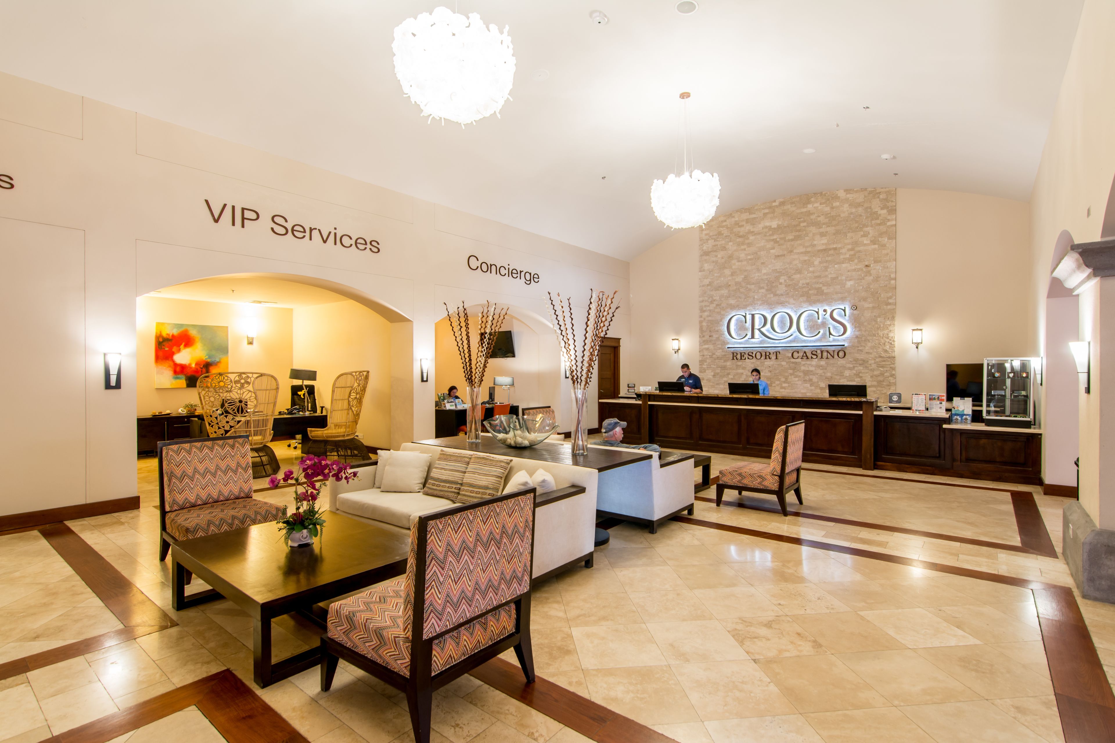 Un hall d’hôtel comprenant un comptoir d’accueil, un espace salon et un panneau indiquant les services VIP.