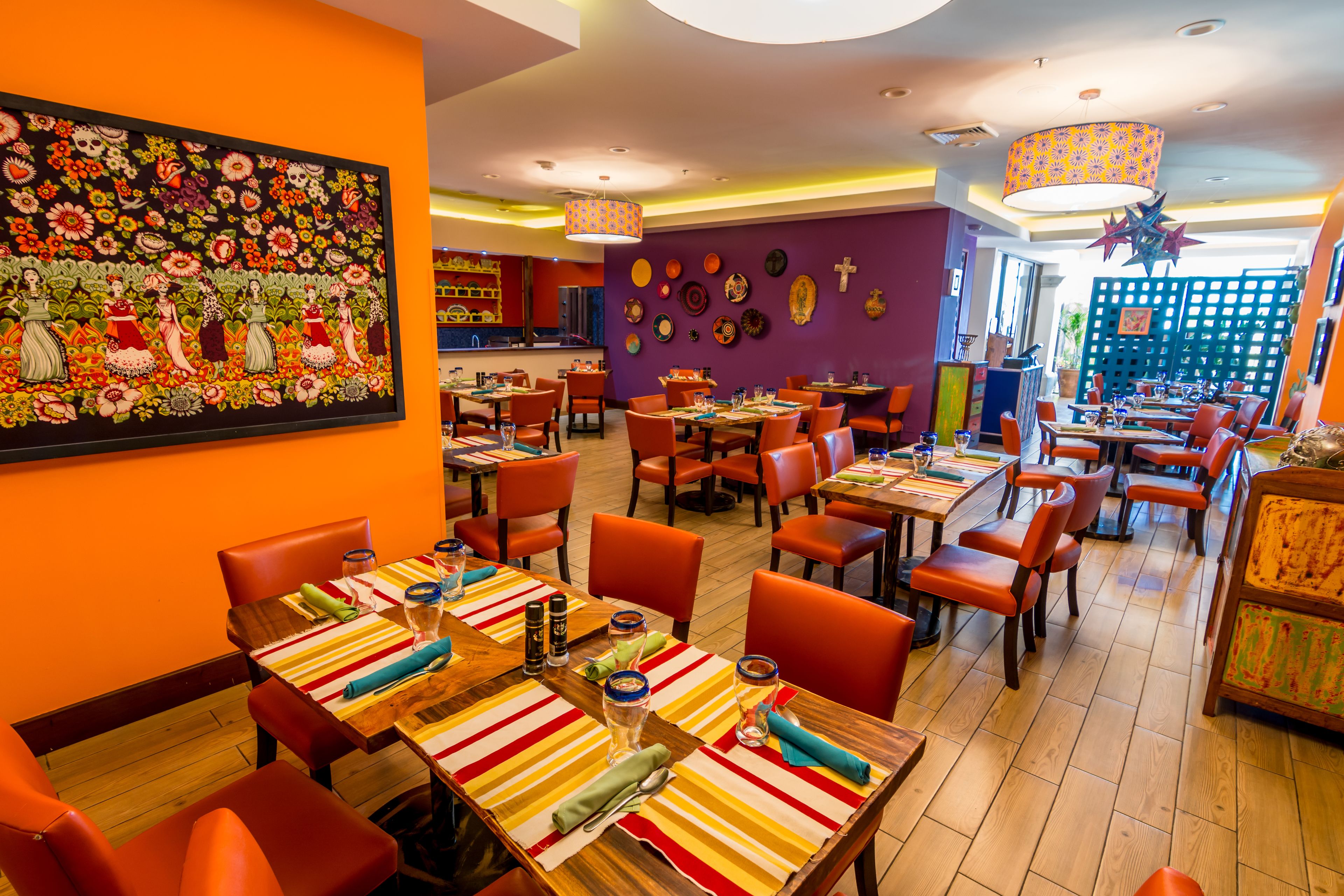 A restaurant with tables and chairs, a large painting on the wall, and various decorative items.