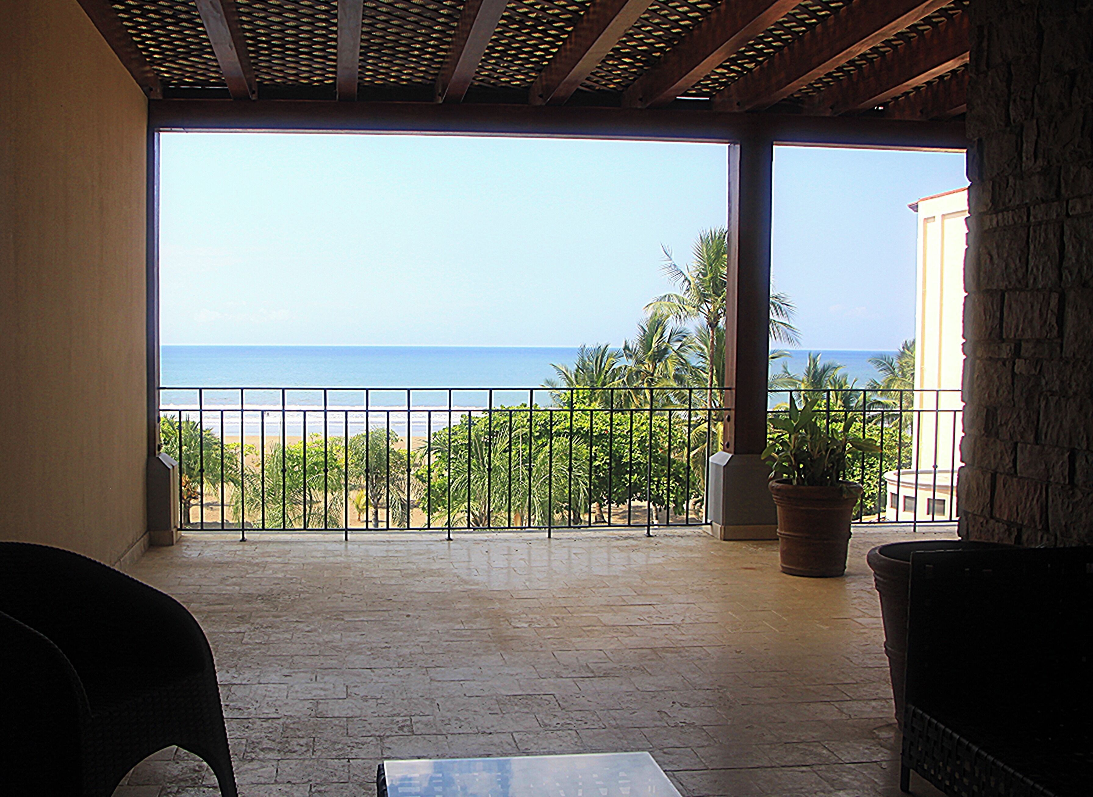 A covered outdoor area with a view of the beach and ocean.