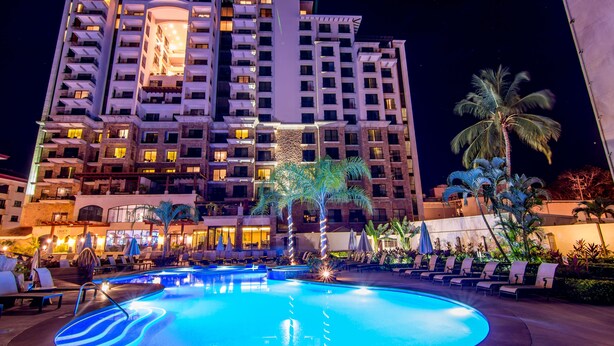 A hotel with a swimming pool, lounge chairs, and palm trees. - Crocs Resort & Casino (Jacó)