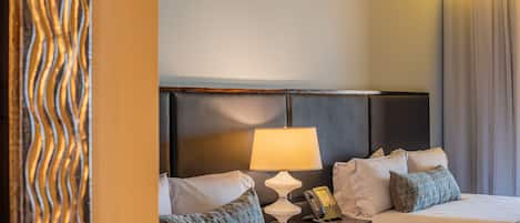 A hotel room with two beds, a bedside lamp, a telephone, and a decorative wall panel.
