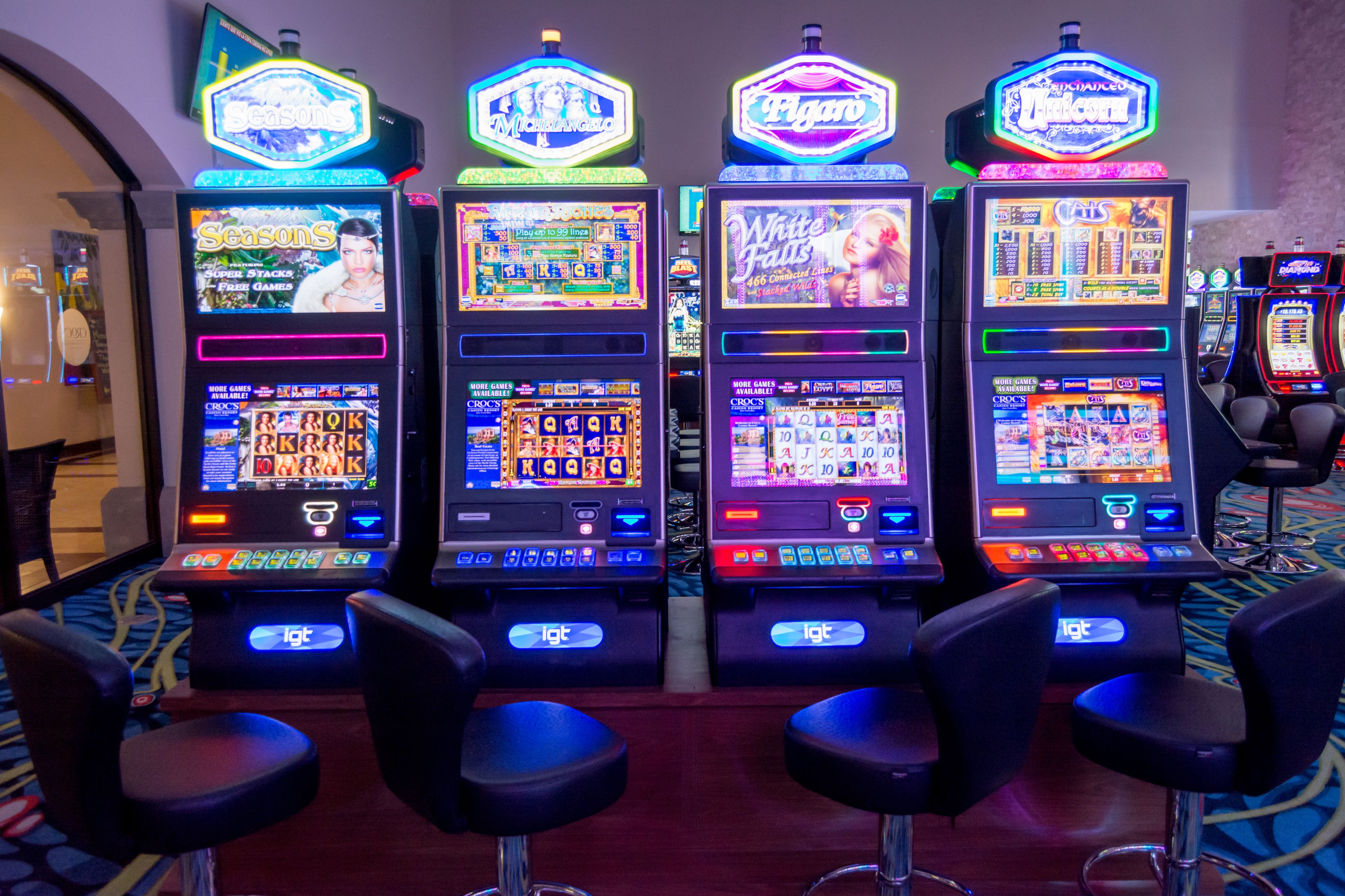 Quatre machines à sous ornées d’enseignes au néon, chacune affichant un titre de jeu différent.