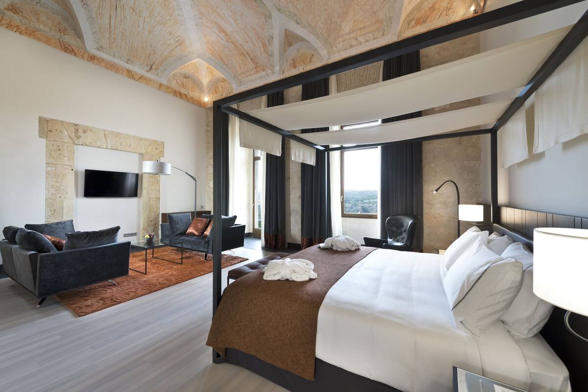 Een moderne hotelkamer met een groot bed, een bank, een bureau en een televisie.