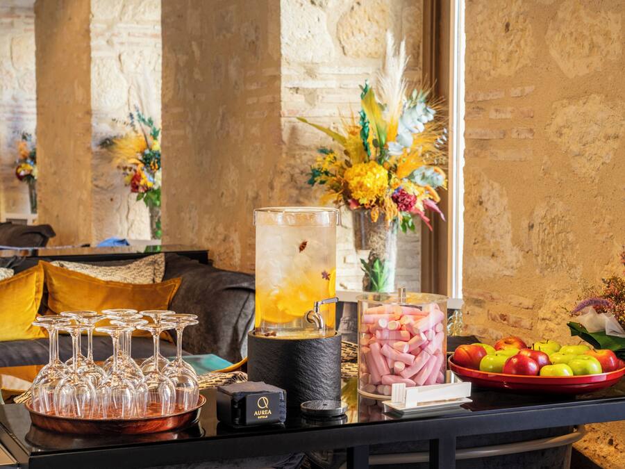 Uma área de bar com dispensador de bebidas, copos e uma cesta de frutas.