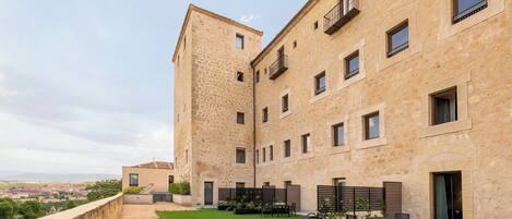 A courtyard with a stone building, outdoor seating, and a view of the city.