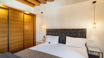 Een moderne hotelkamer met een groot bed, een houten garderobe en een klein nachtkastje.
