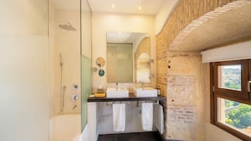 Une salle de bain avec une douche à parois de verre, deux lavabos et un grand miroir.