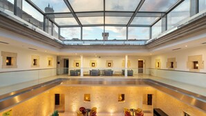 Een ruime atrium met glazen dak, meerdere zithoeken en een centrale trap.