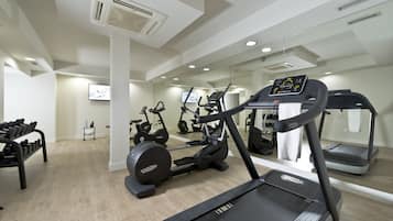 Un gimnasio moderno con cintas de correr, bicicletas estáticas y mancuernas.