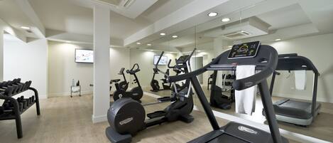 Un gimnasio moderno con cintas de correr, bicicletas estáticas y mancuernas.