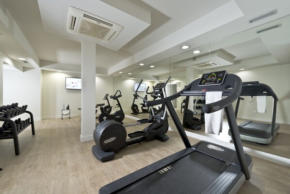 Un gimnasio moderno con cintas de correr, bicicletas estáticas y mancuernas.