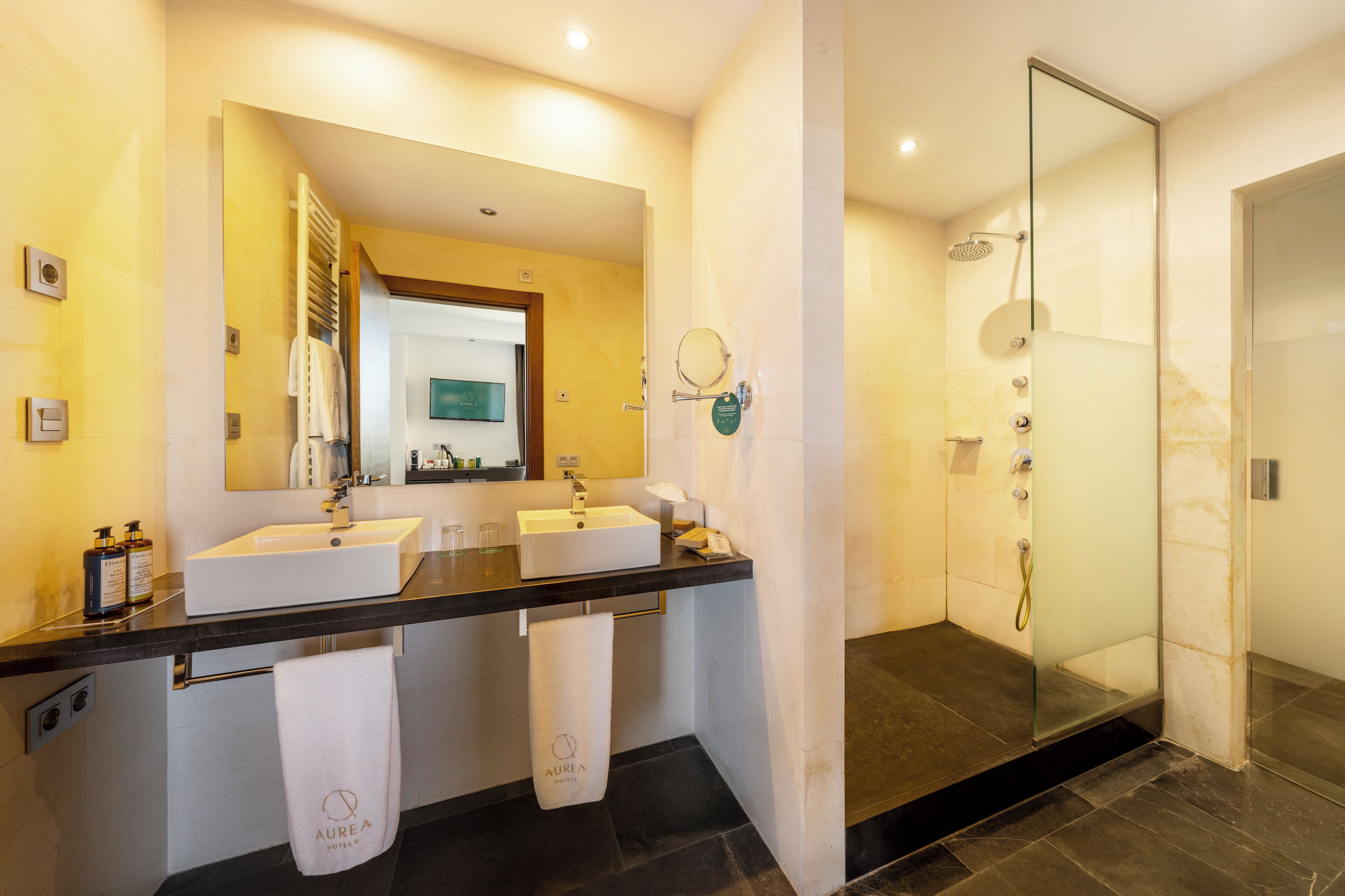 Ein modernes Badezimmer mit zwei Waschbecken, einem großen Spiegel und einer Duschkabine.