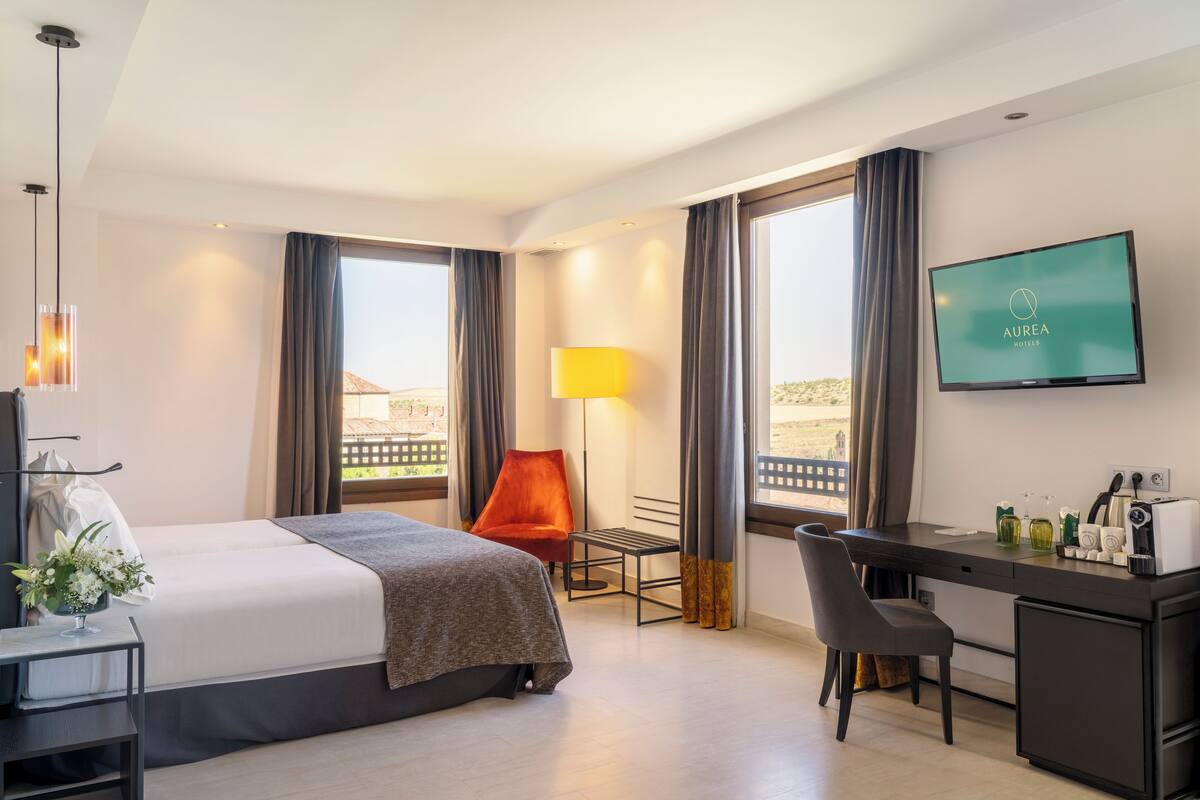 Een hotelkamer met een bed, bureau, stoel, televisie en uitzicht op de stad.