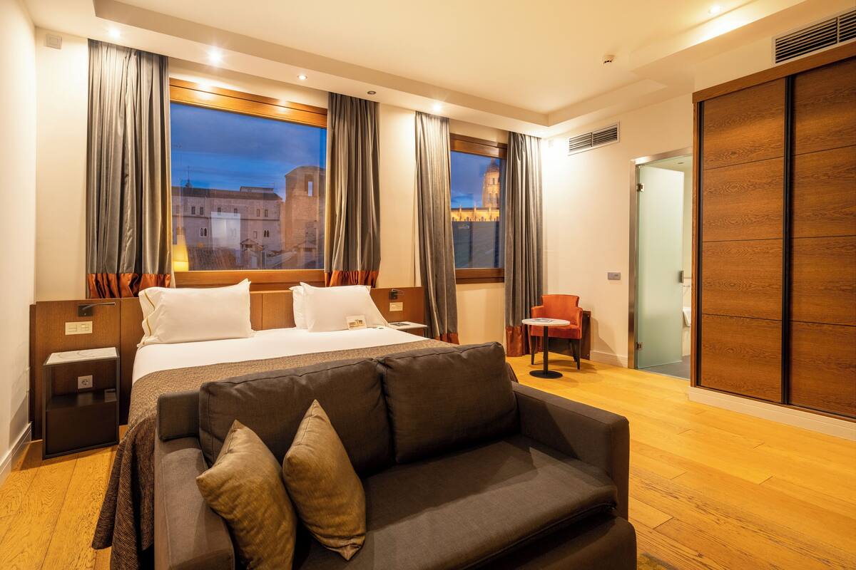 Een hotelkamer met een groot bed, een bank, een stoel en een garderobe.
