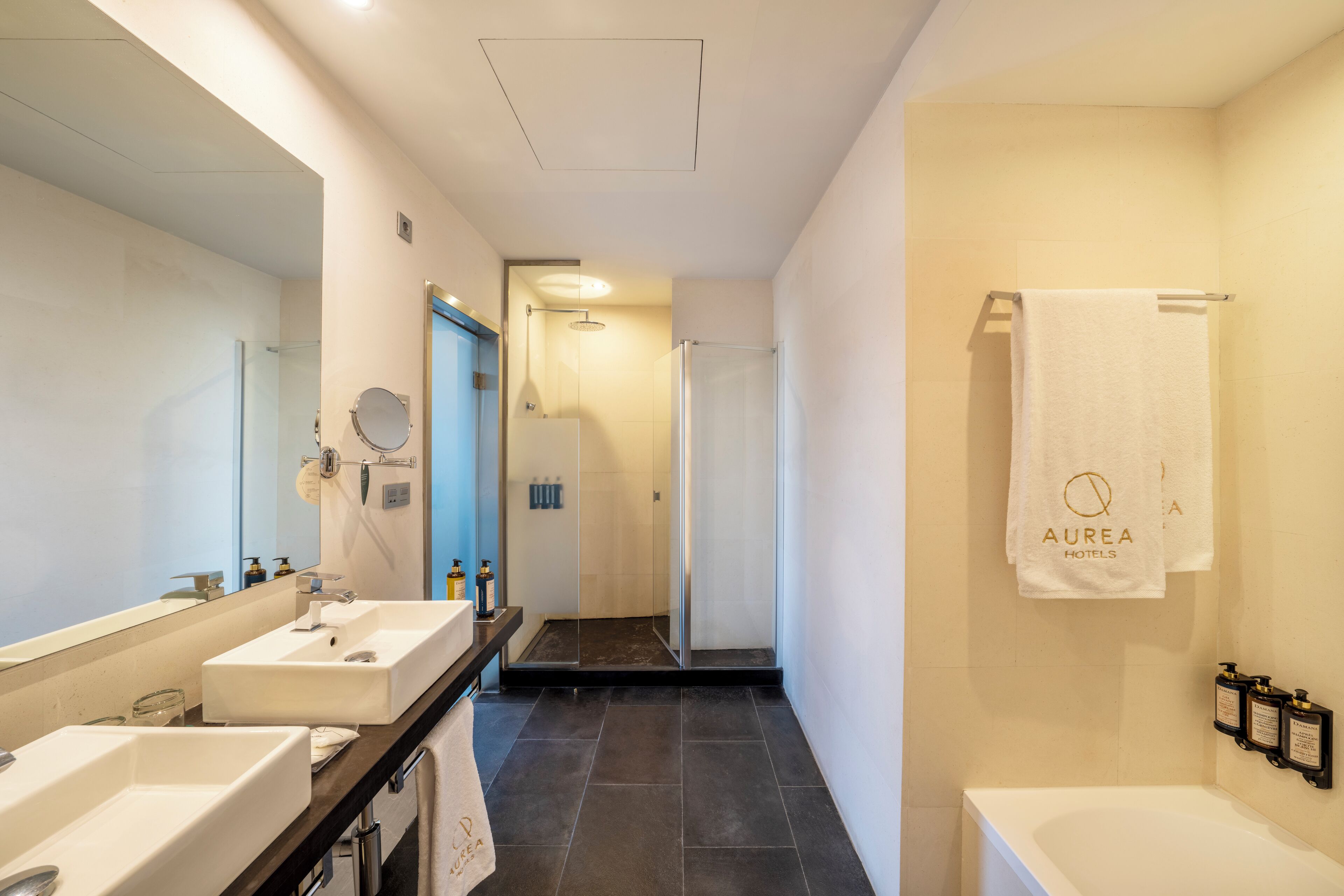 Un baño moderno con dos lavamanos, un espejo grande, ducha y bañera.