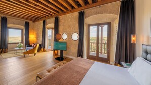 Een ruime kamer met een groot bed, een bank, een televisie en een balkon met uitzicht.